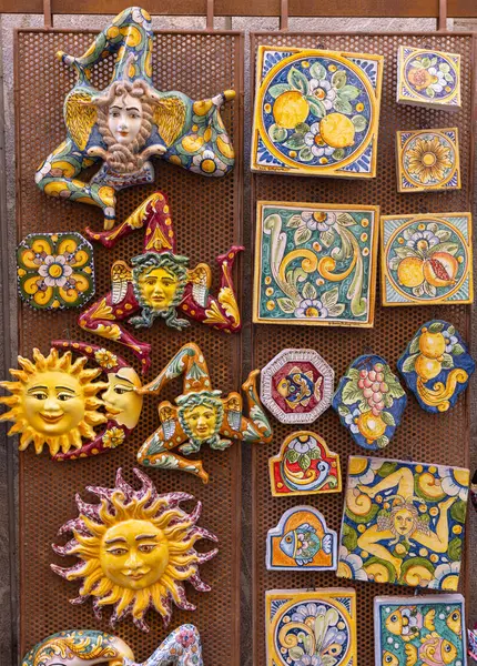 Taormina, Sicilya, İtalya - 28 Nisan 2023: Tarihi köyün duvarlarında renkli seramik güneşler ve trinacria yüzleri sergilenen geleneksel Sicilya hediyelik eşya dükkanı