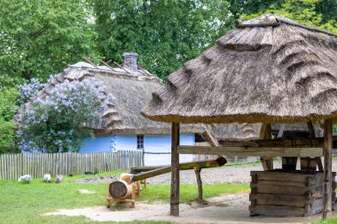 Lublin, Polonya - 23 Mayıs 2022: Lublin Açık Hava Köyü Müzesi 'nde eski Lublin Eyaleti' nin mimari ve etnografik eserleri sergilenmektedir. Ahşap kuyusu olan çiftlik binaları.