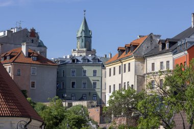 Lublin, Polonya - 24 Mayıs 2022: Wladyslaw Panas Alley ile Eski Şehir 'deki tarihi apartman evleri. Mavi gökyüzünün arka planında Trinitarian Kulesi