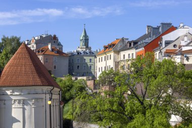 Lublin, Polonya - 24 Mayıs 2022: Wladyslaw Panas Alley ile Eski Şehir 'deki tarihi apartman evleri. Mavi gökyüzünün arka planında Trinitarian Kulesi