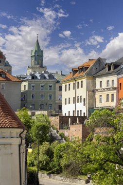 Lublin, Polonya - 24 Mayıs 2022: Eski Şehir 'deki tarihi konutların ve mavi gökyüzünün arka planındaki gotik Trinitarian Kulesi' nin genel görünümü