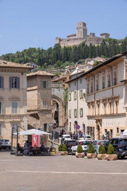 Assisi, İtalya - 12 Haziran 2025: Rocca Maggiore kalesinin manzarası, şehrin yukarısındaki tepedeki ortaçağ kalesinin kalıntıları. Santa Clara Meydanı ve St. George Kapısı 'ndaki eski taş binalar.