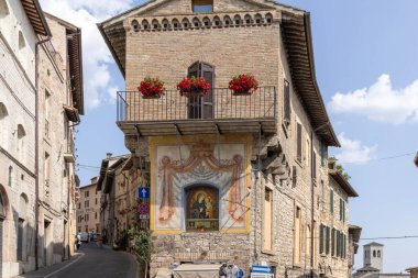 Assisi, İtalya - 12 Haziran 2025: Edicola sacra, küçük bir kilise Madonna ve Çocuk Fresco 'su ile tipik ortaçağ Assisi caddesinde taş evleri ve hediyelik eşya dükkanları olan küçük bir kilise