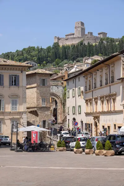 Assisi, İtalya - 12 Haziran 2025: Rocca Maggiore kalesinin manzarası, şehrin yukarısındaki tepedeki ortaçağ kalesinin kalıntıları. Santa Clara Meydanı ve St. George Kapısı 'ndaki eski taş binalar.