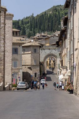 Assisi, İtalya - 12 Haziran 2025: Santa Clara Meydanı ve St. George 's Gate (Portella di San Giorgio). Çiçek saksıları, küçük dükkanlar, ebedi İtalyan cazibesi olan büyüleyici bir meydan.