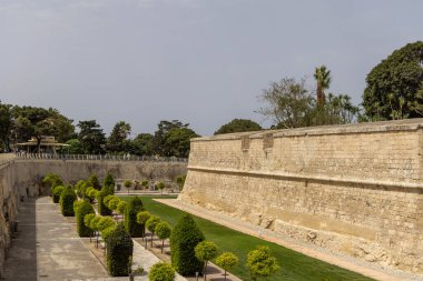 Malta, Mdina - 15 Nisan 2025: Ortaçağ Sessiz Şehri 'ni çevreleyen kireçtaşı şehir duvarları. Etrafında ağaçlar ve çimenler olan güzel bahçeler.