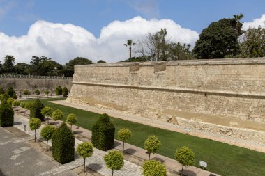 Malta, Mdina - 15 Nisan 2025: Ortaçağ Sessiz Şehri 'ni çevreleyen kireçtaşı şehir duvarları. Etrafında ağaçlar ve çimenler olan güzel bahçeler.