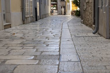Porec, Hırvatistan, Istria - 25 Eylül 2023: Dar, pürüzsüz, cilalanmış kaldırım taşları ile dar bir sokak; yüzyıllar süren ayak izleriyle aşınmış. Şehrin tarihi kalbindeki Ebedi Akdeniz cazibesi