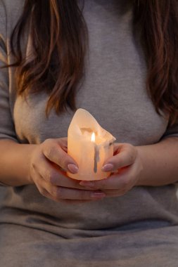 Beyaz mum alevler içinde, kadınlarda eller esrarengiz arkaplanda.