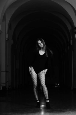 Binanın koridorunda kameraya poz veren güzel genç bir kadın.