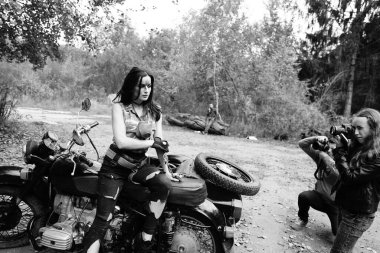 Ormanda motosikletli bir kızın siyah-beyaz fotoğrafı.