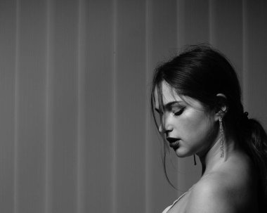 Stüdyoda çıplak bir şekilde poz veren beyaz tişörtlü güzel bir kızın siyah beyaz fotoğrafı.