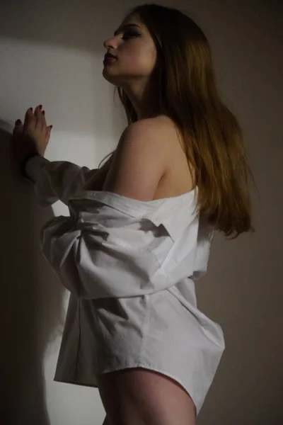 スタジオでポーズをとっている彼女の裸の体に白いシャツを着た美しい少女の写真 — ストック写真