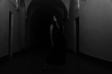 Siyah elbiseli, kameraya poz veren güzel, şehvetli bir kadının siyah beyaz fotoğrafı.