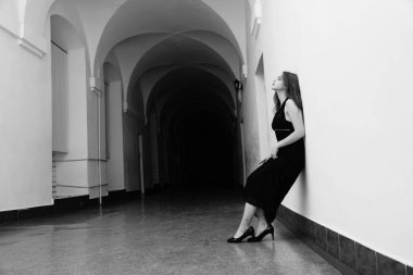 Siyah elbiseli, kameraya poz veren güzel, şehvetli bir kadının siyah beyaz fotoğrafı.