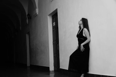 Siyah elbiseli, kameraya poz veren güzel, şehvetli bir kadının siyah beyaz fotoğrafı.