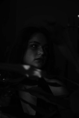 Siyah elbiseli, kameraya poz veren güzel, şehvetli bir kadının siyah beyaz fotoğrafı.