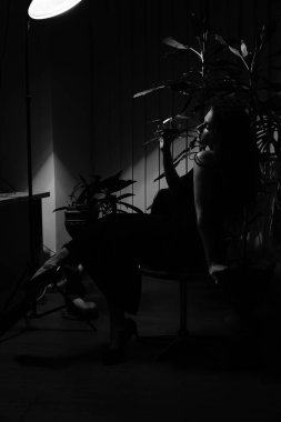 Siyah elbiseli güzel bir kadının siyah beyaz fotoğrafı. Bir bardak viski ile kameraya poz veriyor.