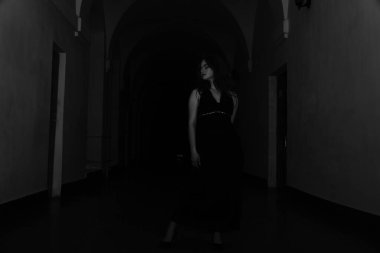 Siyah elbiseli, kameraya poz veren güzel, şehvetli bir kadının siyah beyaz fotoğrafı.