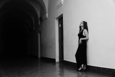 Siyah elbiseli, kameraya poz veren güzel, şehvetli bir kadının siyah beyaz fotoğrafı.