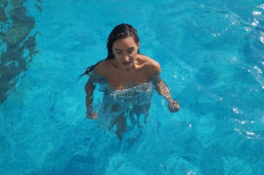 Yüzme havuzunda şeffaf elbiseli seksi bir kız.  