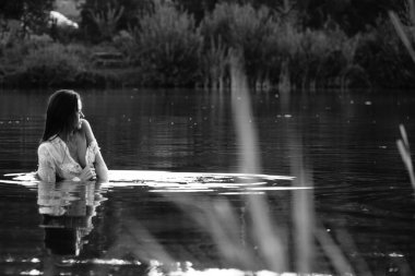Parktaki gölde çekilmiş siyah beyaz bir kız fotoğrafı.