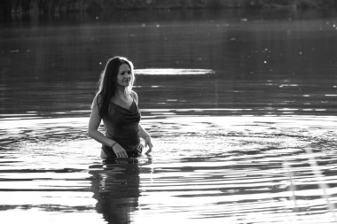 Parktaki gölde çekilmiş siyah beyaz bir kız fotoğrafı. ıslak saçlar ve elbiseler.