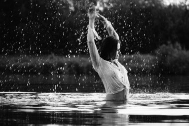 Parktaki gölde çekilmiş siyah beyaz bir kız fotoğrafı. ıslak saçlar ve elbiseler.