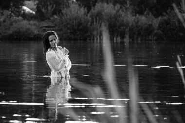 Parktaki gölde çekilmiş siyah beyaz bir kız fotoğrafı. ıslak saçlar ve elbiseler.