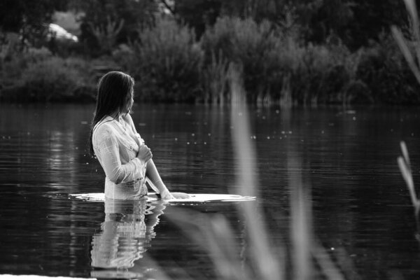 Black and white photo of a girl on a lake in the park.