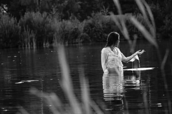 Black and white photo of a girl on a lake in the park.