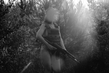 Ormanda yarı çıplak bir asker kızın siyah-beyaz fotoğrafı.