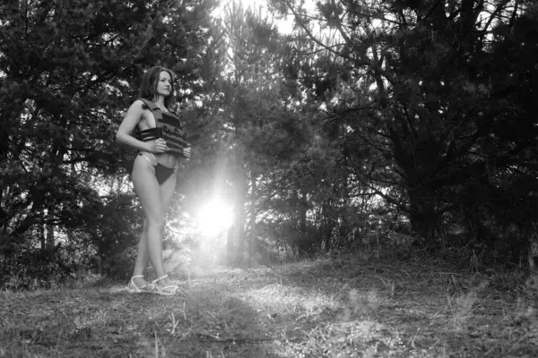 black-white photo of a half-naked soldier girl in the forest