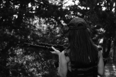 Ormanda yarı çıplak bir asker kızın siyah-beyaz fotoğrafı.