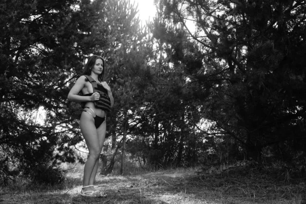 black-white photo of a half-naked soldier girl in the forest