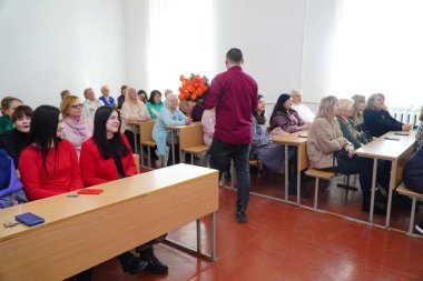 Lutsk, Ukrayna: Ulusal Gıda Teknolojileri Üniversitesi Volyn Profesyonel Koleji 'nde 8 Mart' ta ödül töreninde kadınlara lale dağıtan çocuk