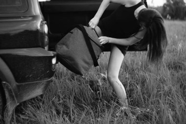 Güzel kız arabadan bir çanta çıkardı.