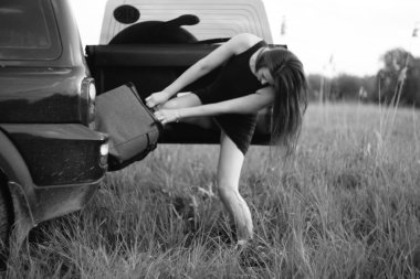 Güzel kız arabadan bir çanta çıkardı.