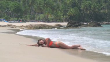 Kız plajda uzanmış güneşleniyor. El falı olan plaj, güneşli bir gün, gülümseyen, kumda oturan