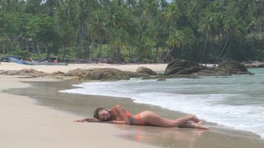 Kız plajda uzanmış güneşleniyor. El falı olan plaj, güneşli bir gün, gülümseyen, kumda oturan