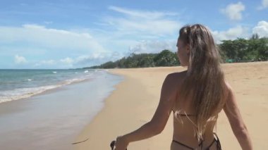 Model kahverengi bikinili ve elinde maskeyle tropikal bir adayı keşfeder. Kumsalın berrak suları, palmiye ağaçları ve sabah güneşinin ve egzotik dinginliğin sinemaları.