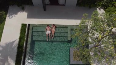 Bir erkek ve bir kız lüks bir havuzda birlikte yatıyorlar.