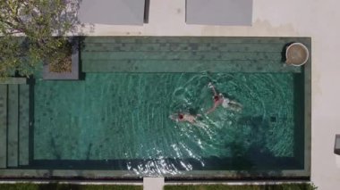 Oğlan ve kız lüks bir havuzda birlikte dönüp yüzüyorlar.