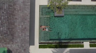 Bir erkek ve bir kız lüks bir havuzda birlikte yatıyorlar.