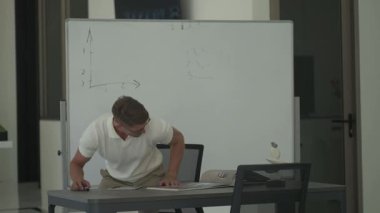 Adam masasında oturup belgeleri inceleyip tablet kullanıyor. Modern, iyi aydınlatılmış bir ofis ortamında odaklanmış çalışma anı