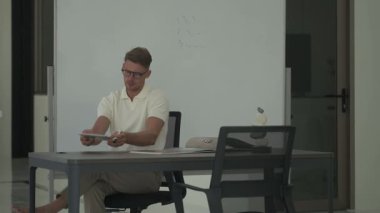 Adam masasında oturup belgeleri inceleyip tablet kullanıyor. Modern, iyi aydınlatılmış bir ofis ortamında odaklanmış çalışma anı