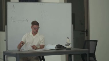 Adam masasında oturup belgeleri inceleyip tablet kullanıyor. Modern, iyi aydınlatılmış bir ofis ortamında odaklanmış çalışma anı