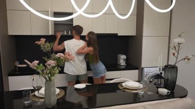 Mutfakta yemek yapmaya hazırlanan bir çift raflarda malzeme arıyor. Evdeki samimi ve neşeli bir an..