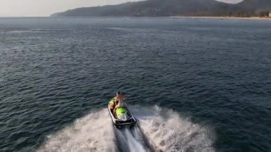 Gün batımında kadın jet ski kullanıyor. Hızlı, özgür ve altın akşam ışığında tropikal enerjiyle dolu..