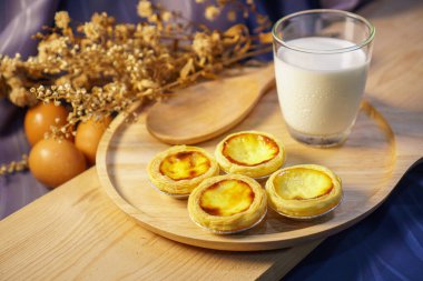 Tahta masada bir bardak sütle yumurtalı tart.